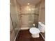 Bathroom featuring a glass enclosed shower and a white toilet on wood-look flooring at 1604 Boswell Ln, New Port Richey, FL 34655