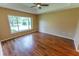 A bedroom featuring wood-look flooring, a ceiling fan, and a large window allowing for ample natural light at 1604 Boswell Ln, New Port Richey, FL 34655