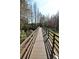Scenic wooden walkway bridge surrounded by lush greenery and trees under a bright sky at 1604 Boswell Ln, New Port Richey, FL 34655