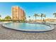 Community pool and patio area overlooking waterfront and palm trees on a sunny day at 31 Island Way # 303, Clearwater Beach, FL 33767