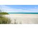 Expansive beach view showcasing the pristine white sand and turquoise waters, with dune grasses in the foreground at 3987 Maceachen Blvd # 133, Sarasota, FL 34233