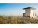 Beach view featuring a lifeguard station, lush dunes, and calm ocean waters under a clear blue sky at 3987 Maceachen Blvd # 133, Sarasota, FL 34233