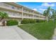 A three story condo building with white railings overlooks a green lawn with flowering bushes and palm trees at 3987 Maceachen Blvd # 133, Sarasota, FL 34233