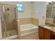 Bathroom with shower, tub, tile accents and vanity with granite countertop at 130 Banyan Bay Dr, St Petersburg, FL 33705