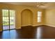 Open living room with wood floors, arched niche, sliding glass doors, and window at 130 Banyan Bay Dr, St Petersburg, FL 33705