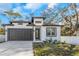 Modern home featuring a dark garage door, white exterior and well-manicured front lawn at 1696 Wilmar Ave, Tarpon Springs, FL 34689