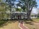Charming single-story home boasts a red brick walkway, mature trees, and a freshly painted exterior at 1758 Winfield Cir, Clearwater, FL 33756