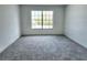 Empty bedroom featuring neutral carpet, a large window with a view of trees and natural light at 19018 Geraci Rd, Lutz, FL 33548