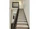 Elegant staircase featuring carpeted steps, dark wood railing, and an open landing, blending style and functionality at 19018 Geraci Rd, Lutz, FL 33548