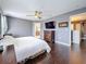 Comfortable main bedroom with hardwood floors, ceiling fan, tv, and adjoining bathroom at 27500 Breakers Dr, Wesley Chapel, FL 33544