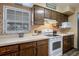 Efficient kitchen featuring vintage wood cabinets, white appliances, and tiled backsplash at 36441 Lake Pasadena Rd, Dade City, FL 33525