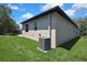 Backyard corner view of the home with a modern air conditioning unit and a lush green lawn at 10019 N Hyaleah, Tampa, FL 33617