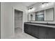 Bathroom featuring double vanity, dark cabinetry, gray countertops, tile flooring, and walk-in closet at 10019 N Hyaleah, Tampa, FL 33617