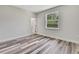 Bright bedroom featuring gray-toned wood-look flooring and a window overlooking a green space at 10019 N Hyaleah, Tampa, FL 33617