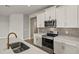 Modern kitchen featuring white cabinets, stainless steel appliances, and stylish backsplash at 12193 Meditation Trl, Venice, FL 34293