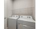 Efficient laundry room with white washer and dryer set, complemented by overhead storage shelving at 12193 Meditation Trl, Venice, FL 34293