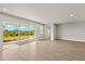 Bright living room with wood-look tile floors, recessed lighting, and glass doors offering outdoor views at 12193 Meditation Trl, Venice, FL 34293