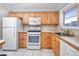 Functional kitchen with white appliances, light wood cabinets, and durable tile flooring at 6025 Shore S Blvd # 311, Gulfport, FL 33707