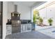Outdoor kitchen with a stainless steel grill, countertop, and adjacent lounging area by the pool at 716 S Lois Ave, Tampa, FL 33609
