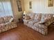 Comfortable living room with floral sofa and love seat and hardwood flooring at 12501 Ulmerton Rd # 140, Largo, FL 33774
