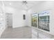 A bright bedroom features white walls, gray flooring, a ceiling fan, and balcony access at 18077 3Rd St, Redington Shores, FL 33708