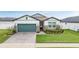 Charming single-story home with a well-manicured lawn, brick driveway, and a stylish teal garage door at 34432 Wynthorne Pl, Wesley Chapel, FL 33545