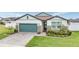 Beautiful single-story home with a well-manicured lawn, brick driveway, and a stylish teal garage door at 34432 Wynthorne Pl, Wesley Chapel, FL 33545