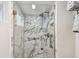 Elegant walk-in shower featuring marbled tile, a glass enclosure, and brushed nickel fixtures at 7 Elgin Pl # 603, Dunedin, FL 34698