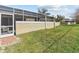 Backyard featuring a partial stucco wall, a screened-in lanai, and green grass at 1581 Amberlea S Dr, Dunedin, FL 34698