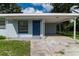 Inviting single-story home with a covered entrance and carport, set against a lush green backdrop at 8902 Temple Park Dr, Tampa, FL 33637