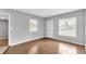 Bright empty living room with new light wood floors, neutral gray paint, a door and two windows at 8902 Temple Park Dr, Tampa, FL 33637