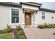 Charming front entry with a brown door, adorned with a wreath and complemented by brick pavers and landscaping at 4639 Garofalo Rd, Wesley Chapel, FL 33543