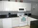 A kitchen featuring white appliances, white cabinets, black countertops and tile flooring at 6033 34Th W St # 45, Bradenton, FL 34210