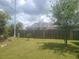 A fenced backyard with a screened pool enclosure and mature trees at 1279 Dinnerbell E Ln, Dunedin, FL 34698