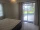 This bedroom features a sliding glass door to the screened lanai, tiled floors, and neutral paint at 1279 Dinnerbell E Ln, Dunedin, FL 34698