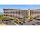 Large condominium building with parking area and palm trees in a waterfront community at 19451 Gulf Blvd # 204, Indian Shores, FL 33785