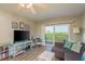 An open living room with a coastal design, a large TV, and a sliding glass door that leads to the outside at 19451 Gulf Blvd # 204, Indian Shores, FL 33785
