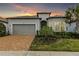 Charming single-story home featuring a brick driveway, lush landscaping, and a two-car garage at 19771 Ship Wheel Way, Land O Lakes, FL 34638