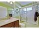 Bright bathroom with a granite countertop vanity and a shower-tub combo with glass doors at 9413 Swift Creek Cir, Dover, FL 33527