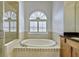 Bathroom features a soaking tub with tile surround, a bright window, and custom cabinetry at 9413 Swift Creek Cir, Dover, FL 33527