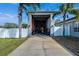 Garage structure with a concrete driveway, some fencing, and palm trees on either side at 9413 Swift Creek Cir, Dover, FL 33527