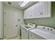 Well-lit laundry room with white cabinets, washer, dryer, and a utility sink at 9413 Swift Creek Cir, Dover, FL 33527