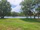 This is a view of the luscious green backyard, leading to the sparkling blue lake at 1919 Blue River Rd, Holiday, FL 34691