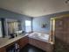Well-lit bathroom with a soaking tub and glass-enclosed shower at 1919 Blue River Rd, Holiday, FL 34691