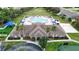 Aerial view of a community clubhouse, pool, volleyball court, and manicured grounds with palm trees at 1919 Blue River Rd, Holiday, FL 34691