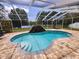 Lakeside pool is screened in with a waterfall feature and steps leading into the water at 1919 Blue River Rd, Holiday, FL 34691