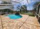 This screened-in pool features a brick surround, waterfall feature, and relaxing lakeside views at 1919 Blue River Rd, Holiday, FL 34691