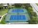 Aerial view of two well-maintained tennis courts surrounded by green landscaping and fencing at 1919 Blue River Rd, Holiday, FL 34691