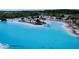 Aerial view of community crystal lagoon with beach seating, island with palm trees, and white sand at 32535 Turtle Grace Loop, Wesley Chapel, FL 33545