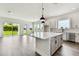 Open-concept kitchen with white cabinets, island, stainless steel appliances, and backyard view at 5283 Everlong Dr, Apollo Beach, FL 33572